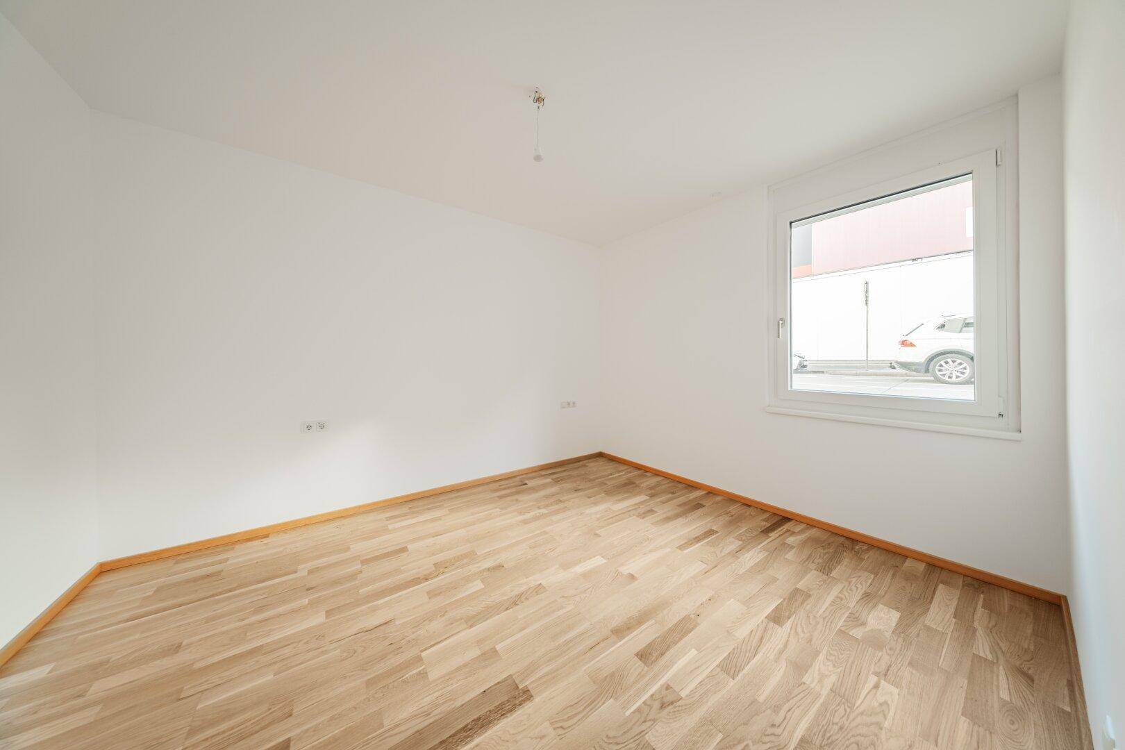 Ruhiger, heller Raum mit Parkettboden und einem Fenster, bietet eine gemütliche und private Atmosphäre.