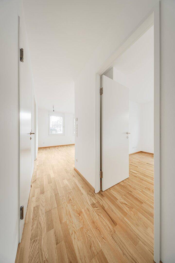 Heller Flur mit Parkettboden und weißen Türen, der zu den verschiedenen Zimmern der Wohnung führt.
