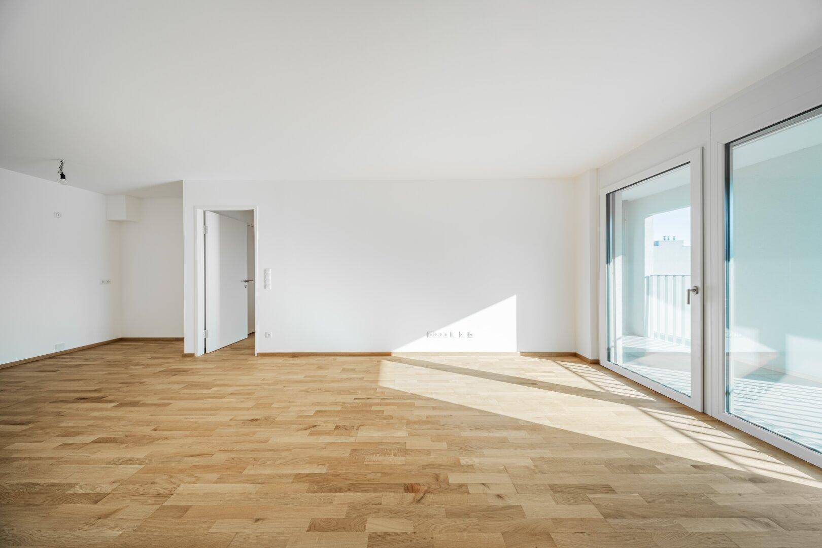 Geräumiger, unmöblierter Raum mit viel Tageslicht und Holzboden.
