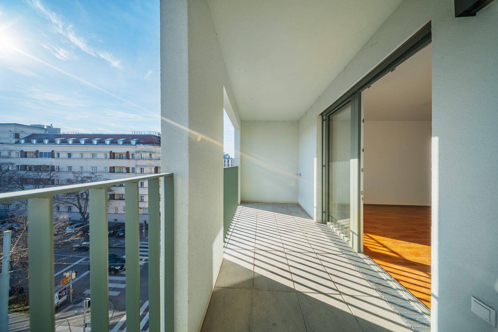 Langer Balkon mit Fliesenboden und Blick auf die Stadt und die Straße.