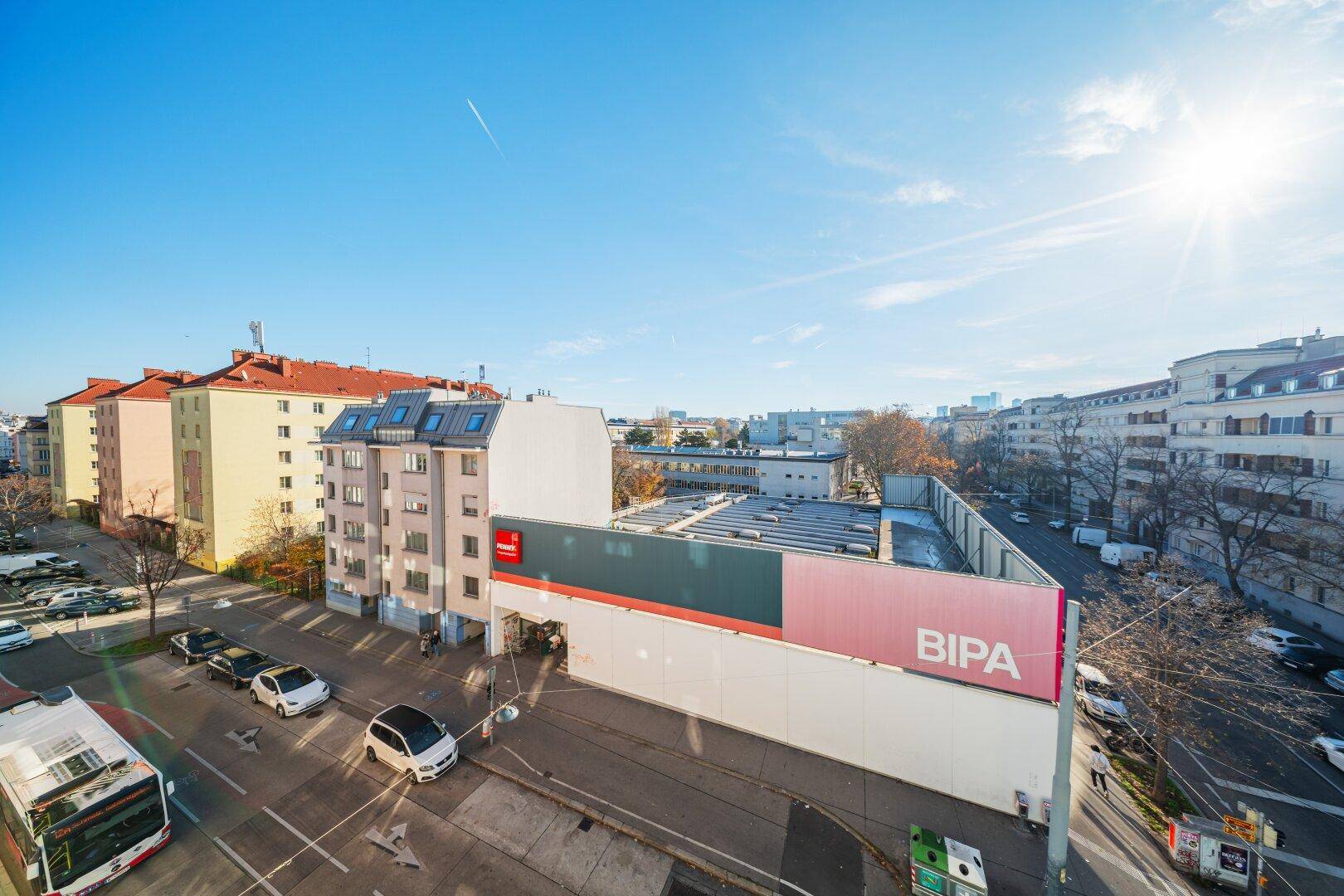 Weitläufiger Blick über die Stadt mit Gebäuden und Straßenverkehr unter blauem Himmel.