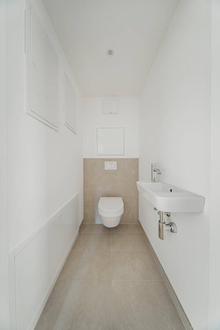 Modernes Gäste-WC mit wandhängender Toilette und kleinem Waschbecken.