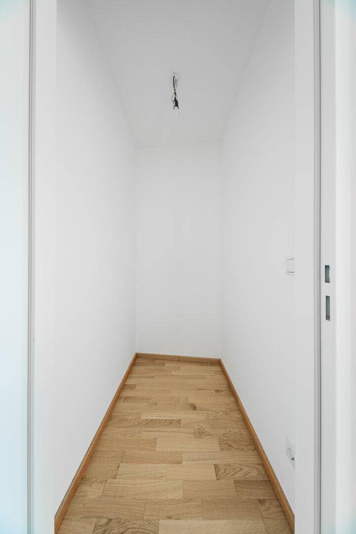 Kleiner, leerer Abstellraum mit Parkettboden und weißen Wänden.