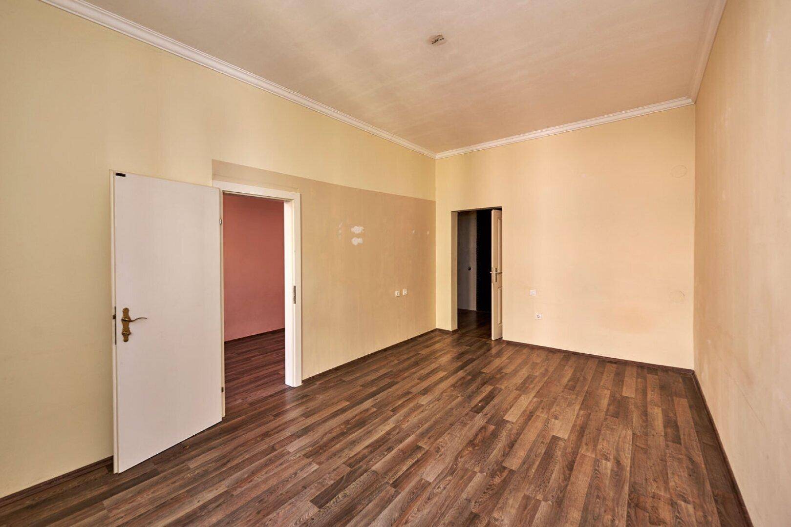 Geräumiges Zimmer mit Holzboden und zwei Türöffnungen, ideal für flexible Nutzung.