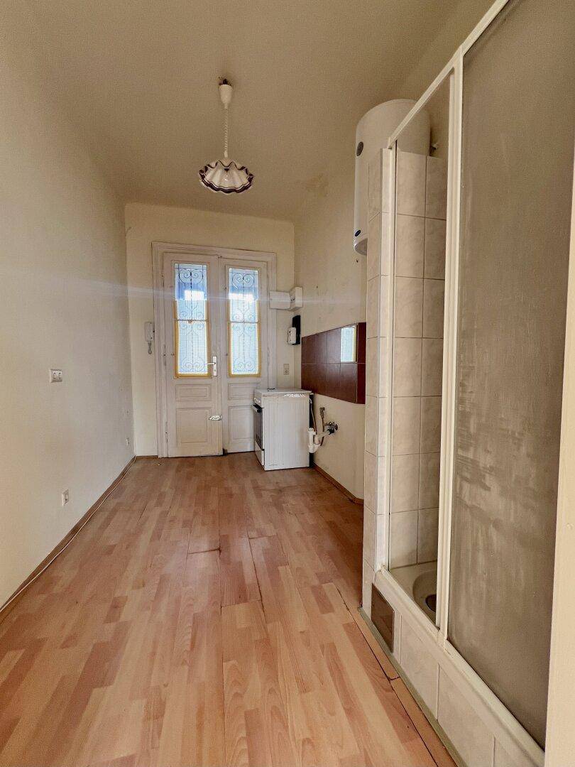 Funktionales Badezimmer mit Duschkabine, Warmwasserboiler und Waschmaschine, mit Zugang zu einem weiteren Raum.