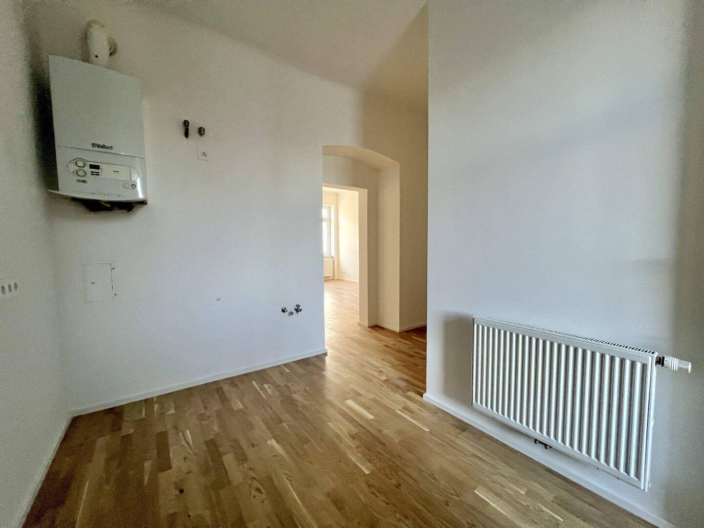 Heller Flur mit Parkettboden und einer Gastherme, der den Zugang zu weiteren Räumen ermöglicht.