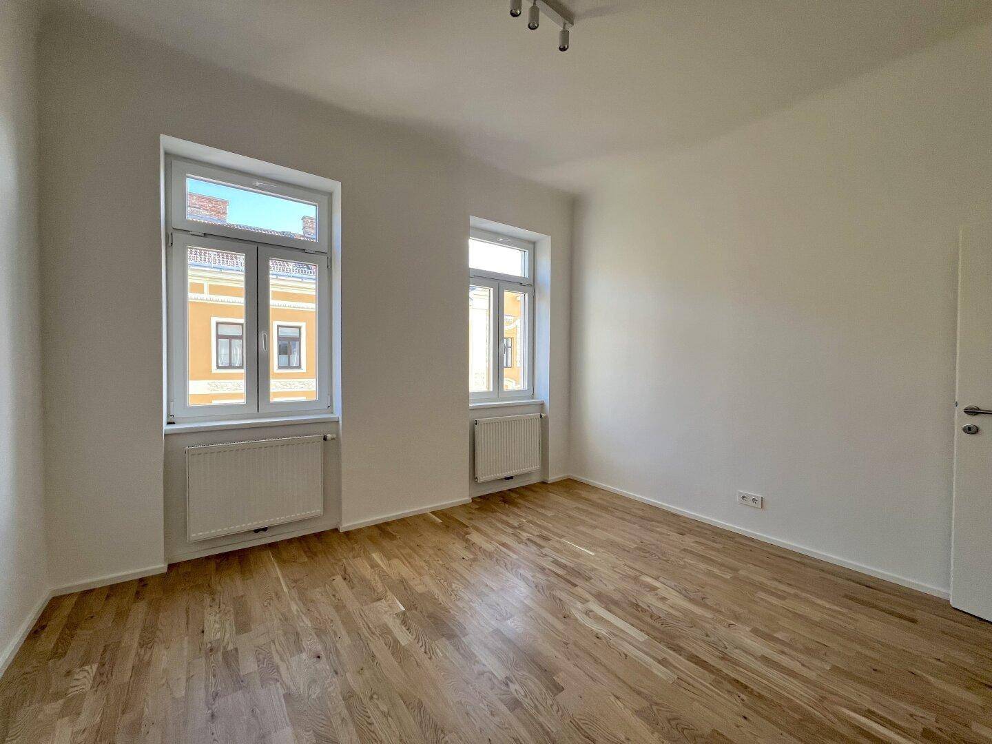 Großzügiges Zimmer mit schönem Parkett und Blick auf die umliegende historische Architektur der Stadt.
