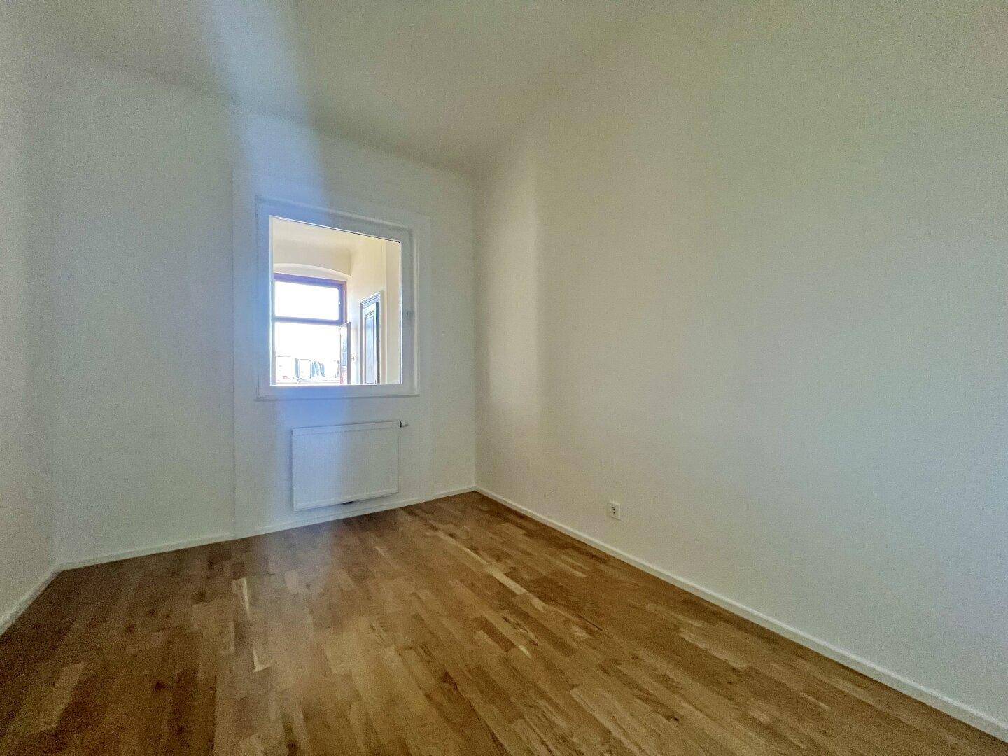 Gemütliches Zimmer mit Parkettboden und einem Fenster, ideal als Schlafzimmer oder Arbeitsbereich nutzbar.