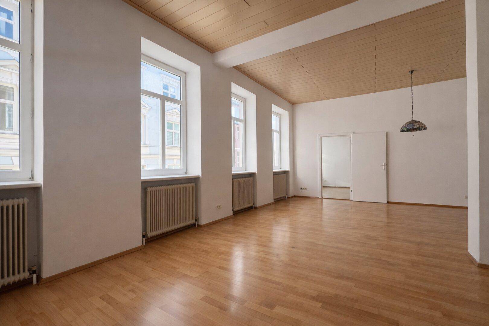 Heller Wohnraum mit Holzbalkendecke und Parkettboden, bietet viel Potenzial für individuelle Einrichtung.
