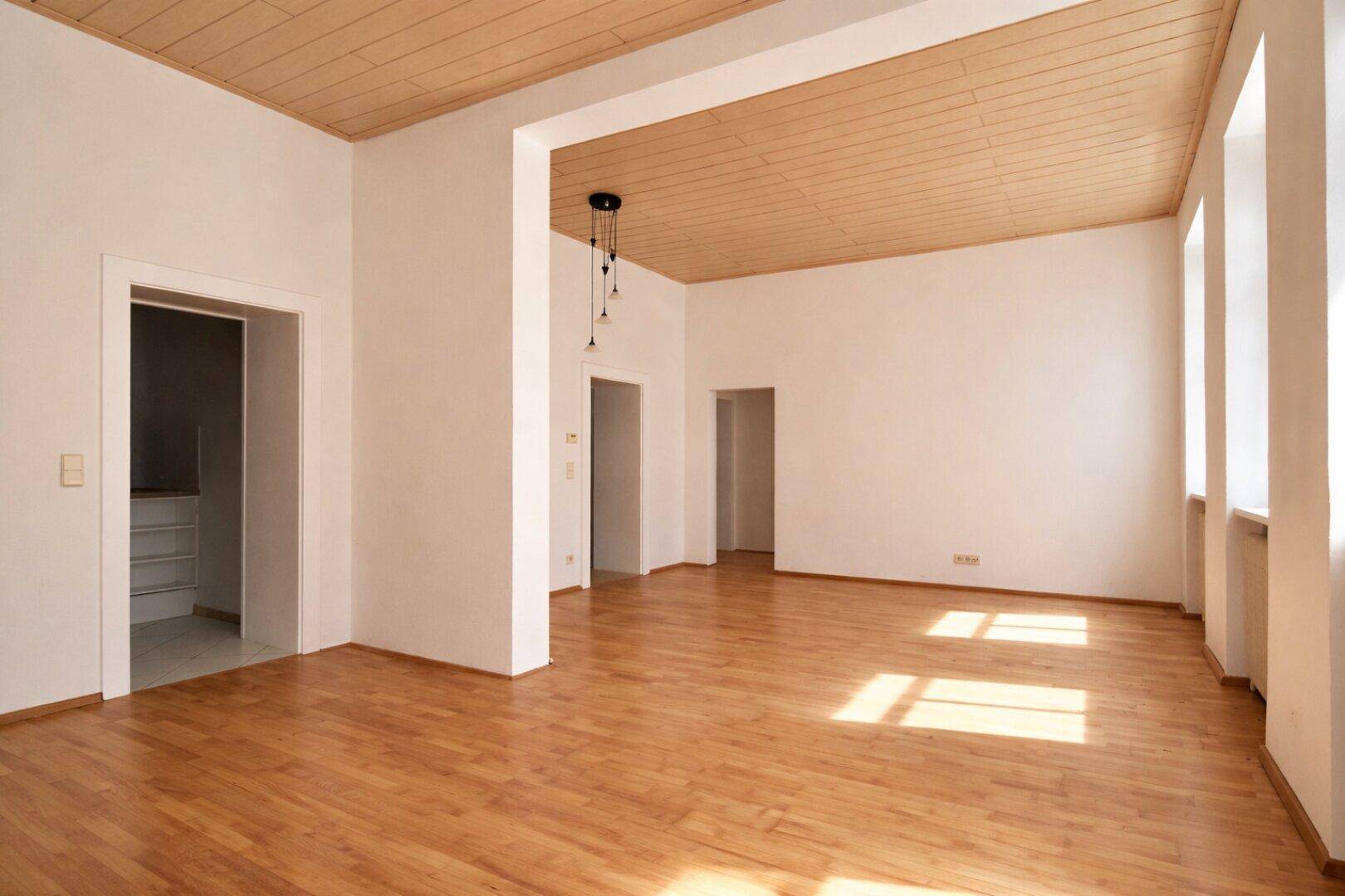 Großzügiger, heller Raum mit Parkettboden und Holzdecke, ideal für offenes Wohnen.