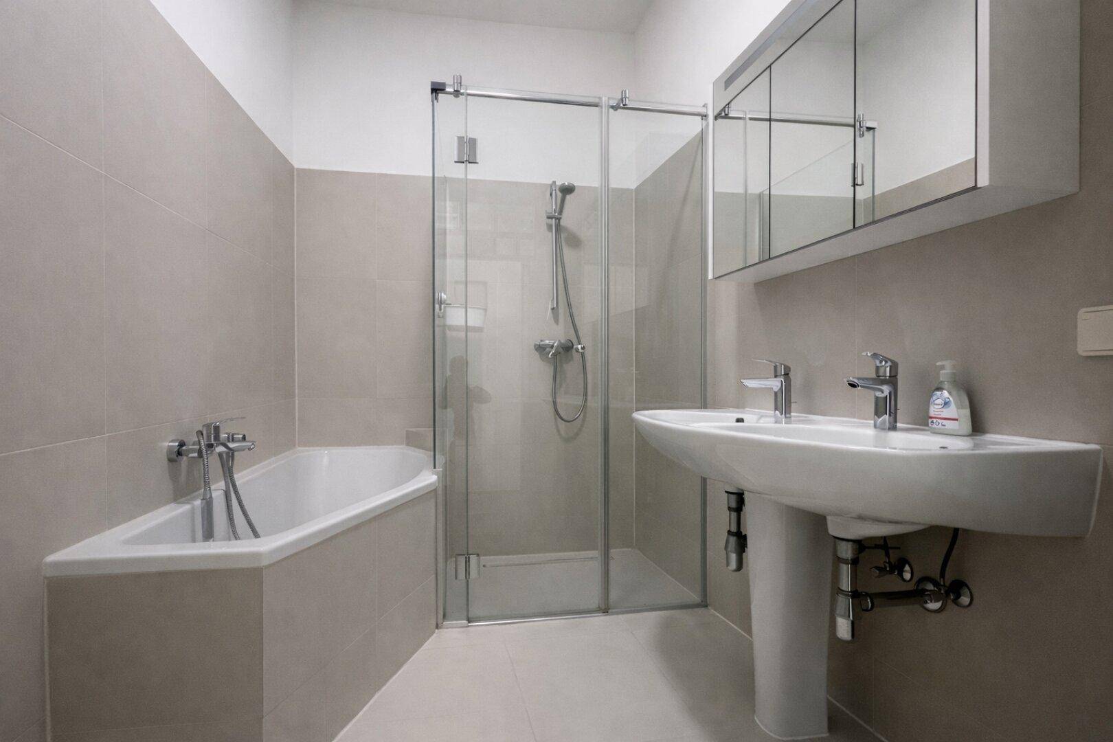 Modernes Badezimmer mit Badewanne, Duschkabine und Waschbecken, in neutralen Farbtönen gehalten.