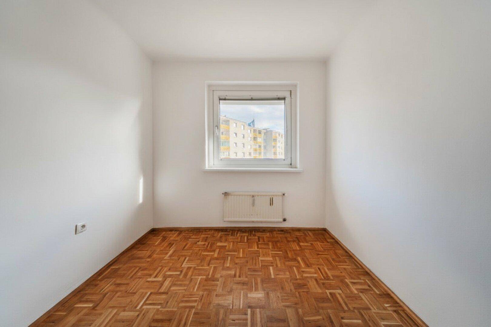 Kleiner, heller Raum mit Parkettboden und Fenster, ideal als Schlaf- oder Arbeitszimmer.