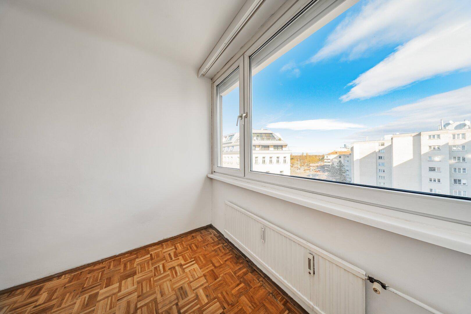 Heller Raum mit Parkettboden und großem Fenster mit weitem Blick.