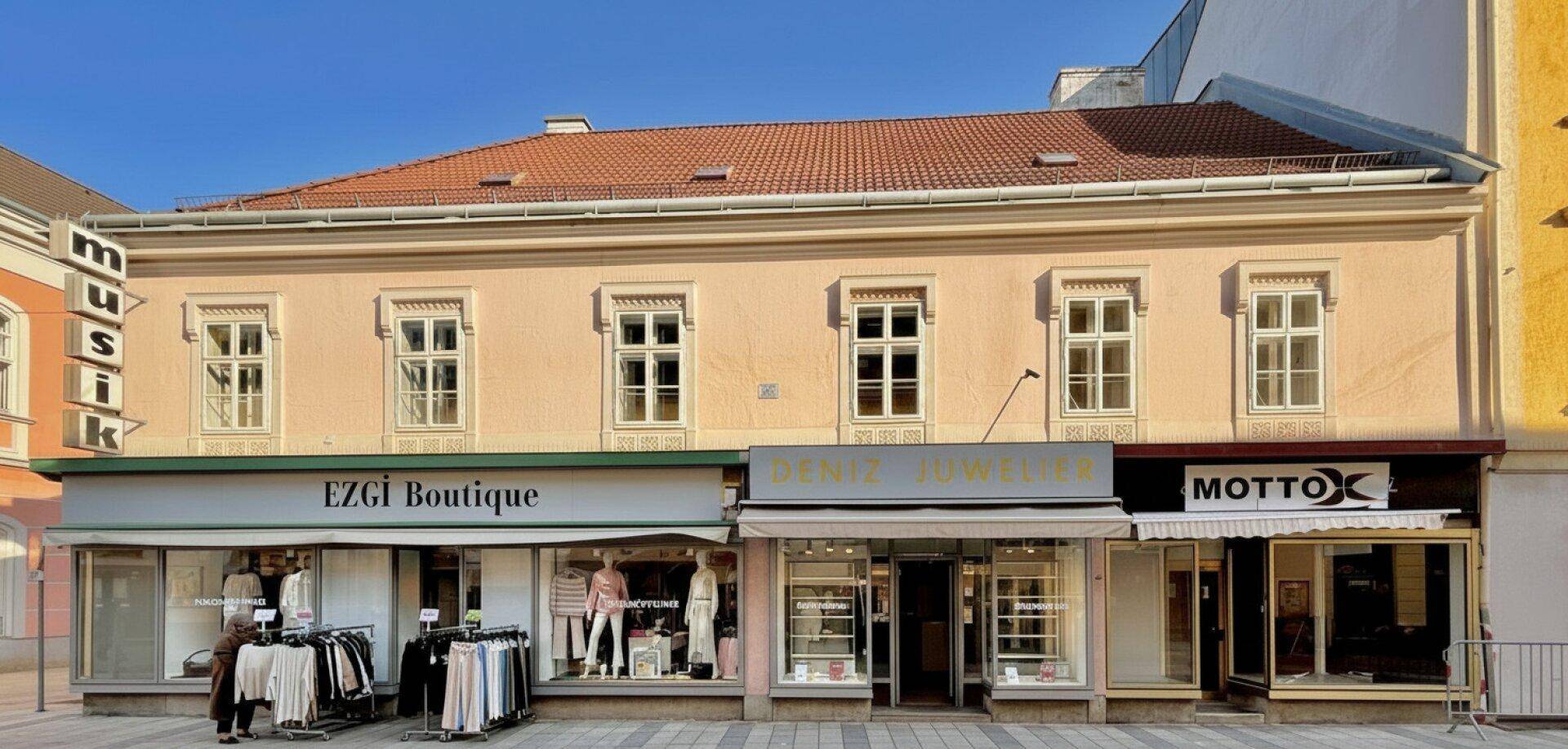 Historisches Geschäftsgebäude mit mehreren Geschäften im Erdgeschoss und Wohnungen darüber.