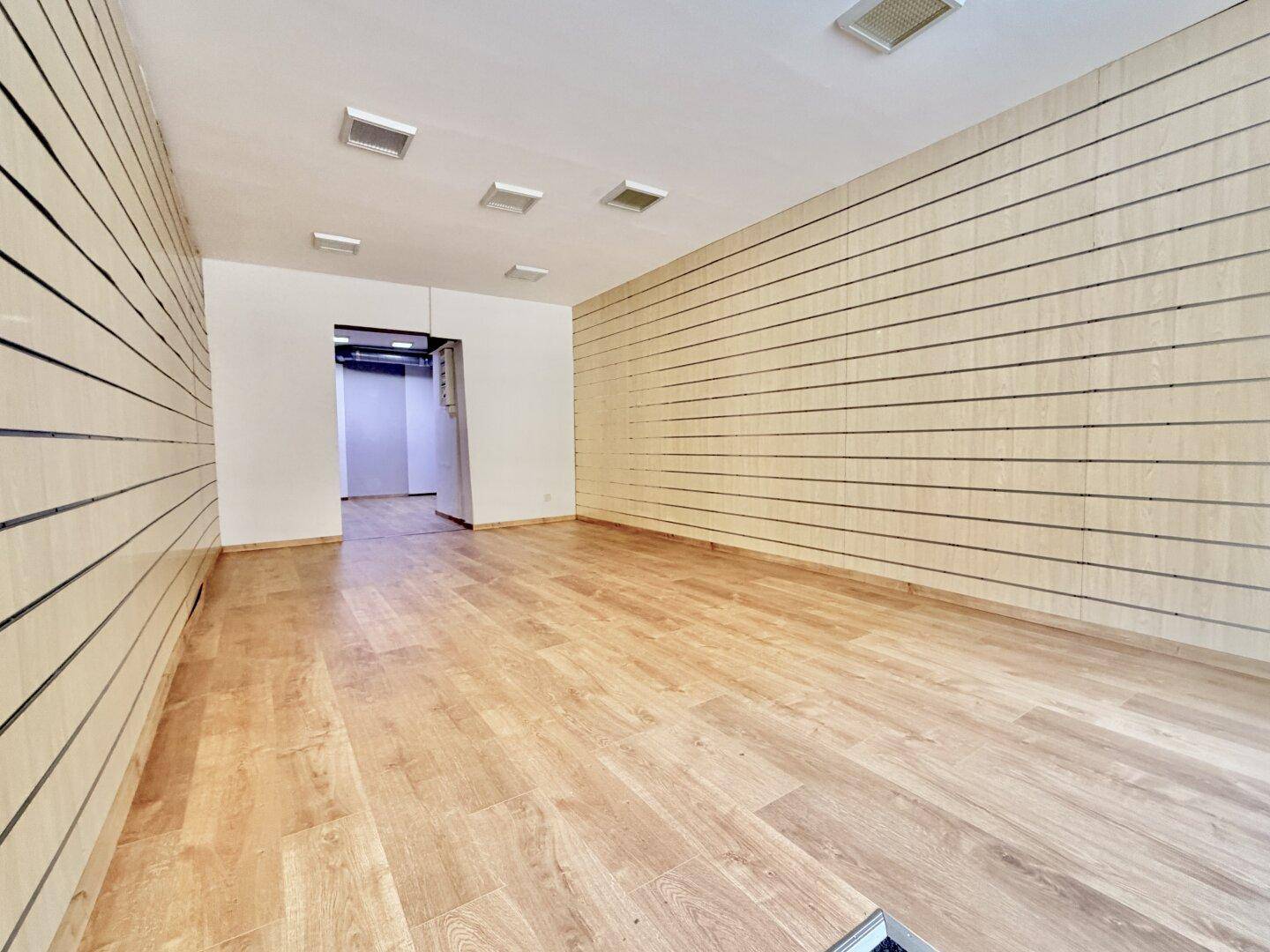 Geräumiger Ladenraum mit Holzboden und gestreiften Wänden, ideal für ein neues Geschäftskonzept.
