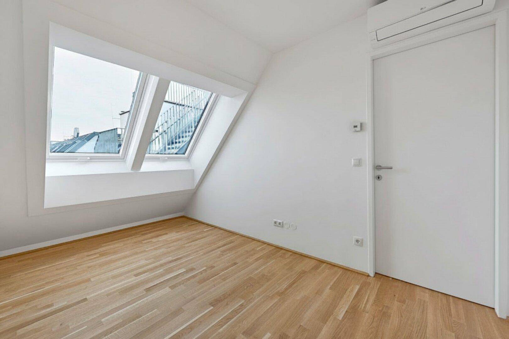 Lichtdurchfluteter Raum mit Dachfenstern, Parkettboden und Klimaanlage, ideal für ein ruhiges Arbeits- oder Schlafzimmer.