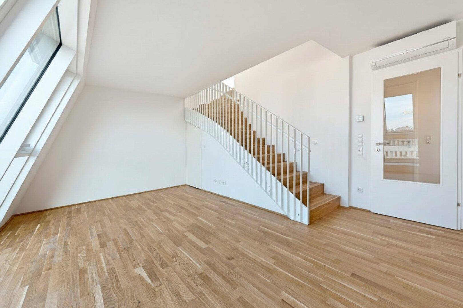 Lichtdurchfluteter Raum mit Holztreppe, Parkettboden und Klimaanlage, ideal für ein modernes Wohnkonzept.