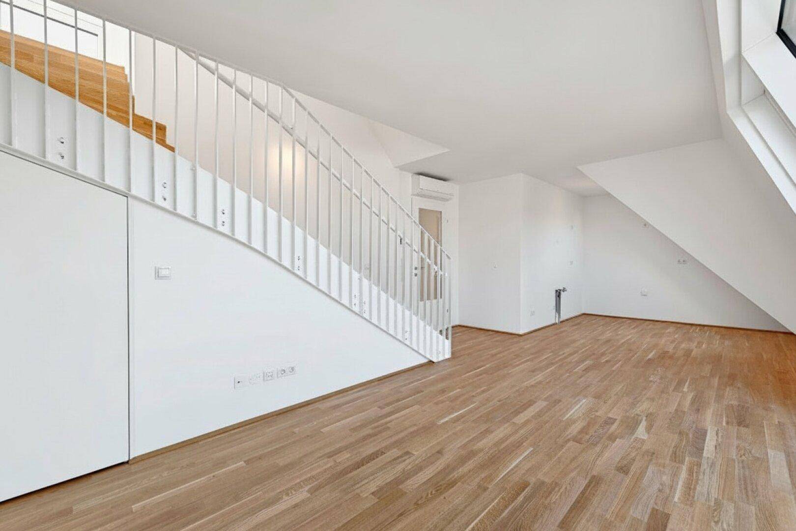 Geräumiger, heller Raum mit moderner Treppe und neuem Parkettboden, bietet eine offene und einladende Atmosphäre.