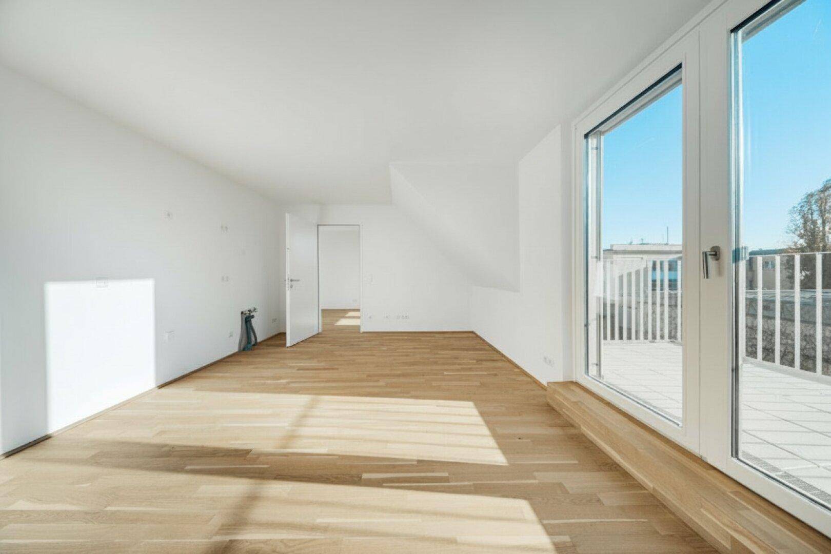 Lichtdurchfluteter Raum mit Holzboden und breiter Terrassentür, bereit für individuelle Gestaltung.