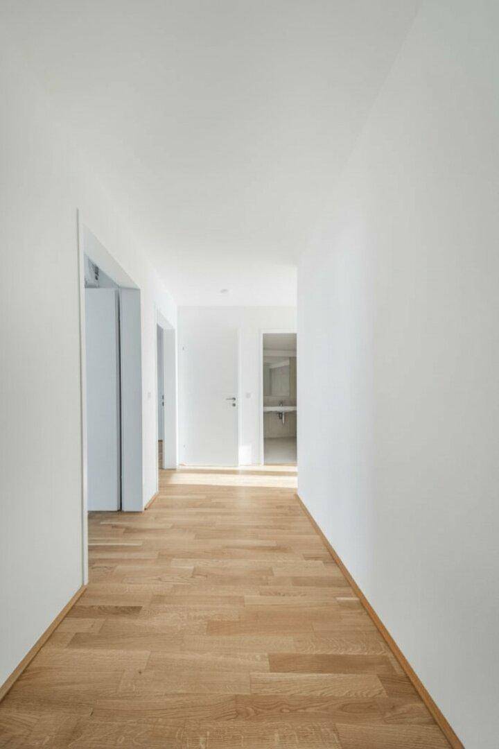 Heller Flur mit Holzboden und Zugang zu verschiedenen Räumen.