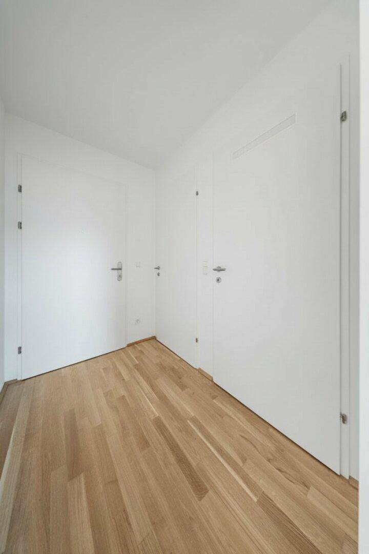 Heller Flur mit Parkettboden und mehreren Türen, verbindet die verschiedenen Räume der Wohnung.