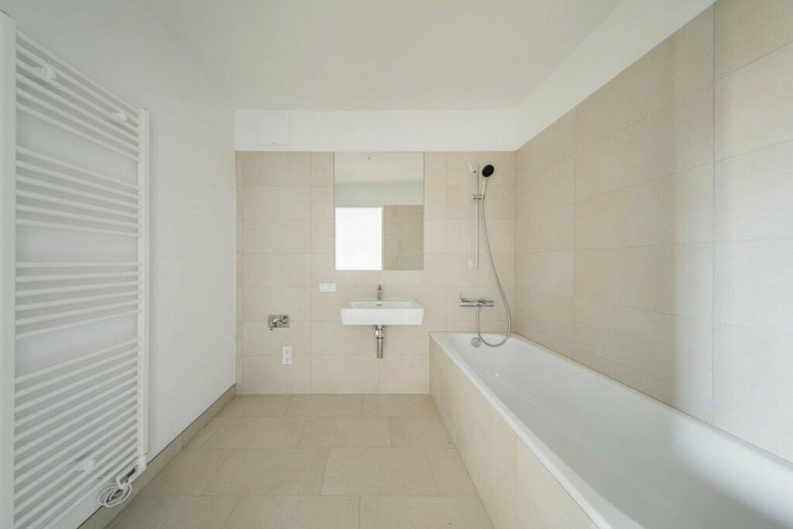 Helles Badezimmer mit Badewanne, Waschbecken und beheiztem Handtuchhalter, in gutem Zustand.