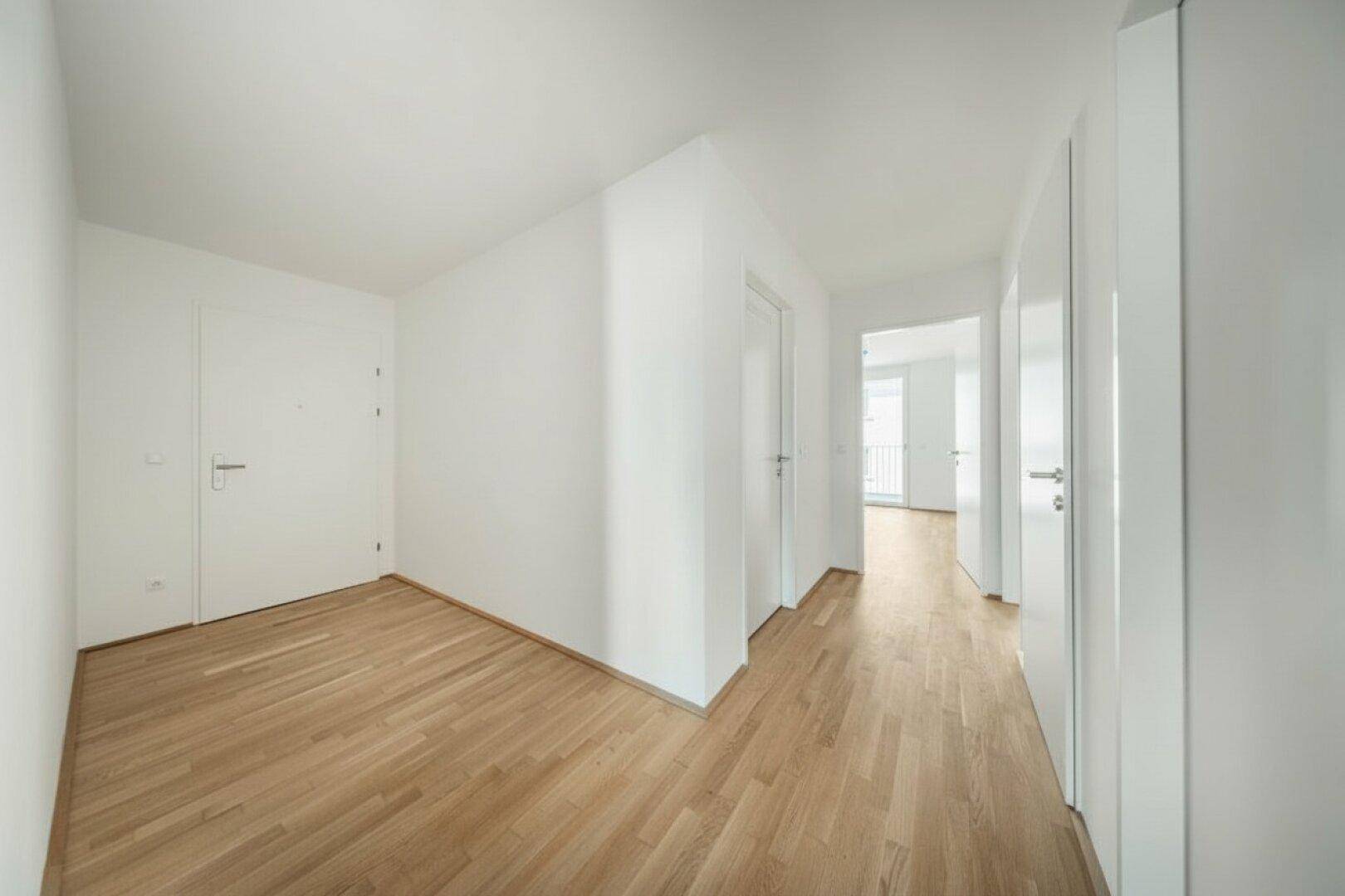 Geräumiger Flur mit Holzboden und weißen Türen, der vielseitig nutzbar ist.