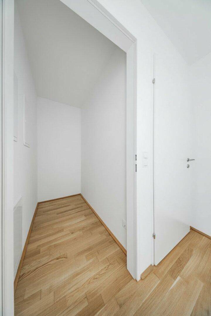 Praktischer Abstellraum mit hellem Parkettboden und weißen Wänden.