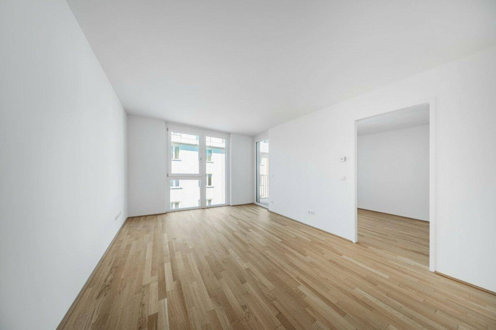Geräumiger, unmöblierter Raum mit Parkettboden und großen Fenstern für viel Tageslicht.