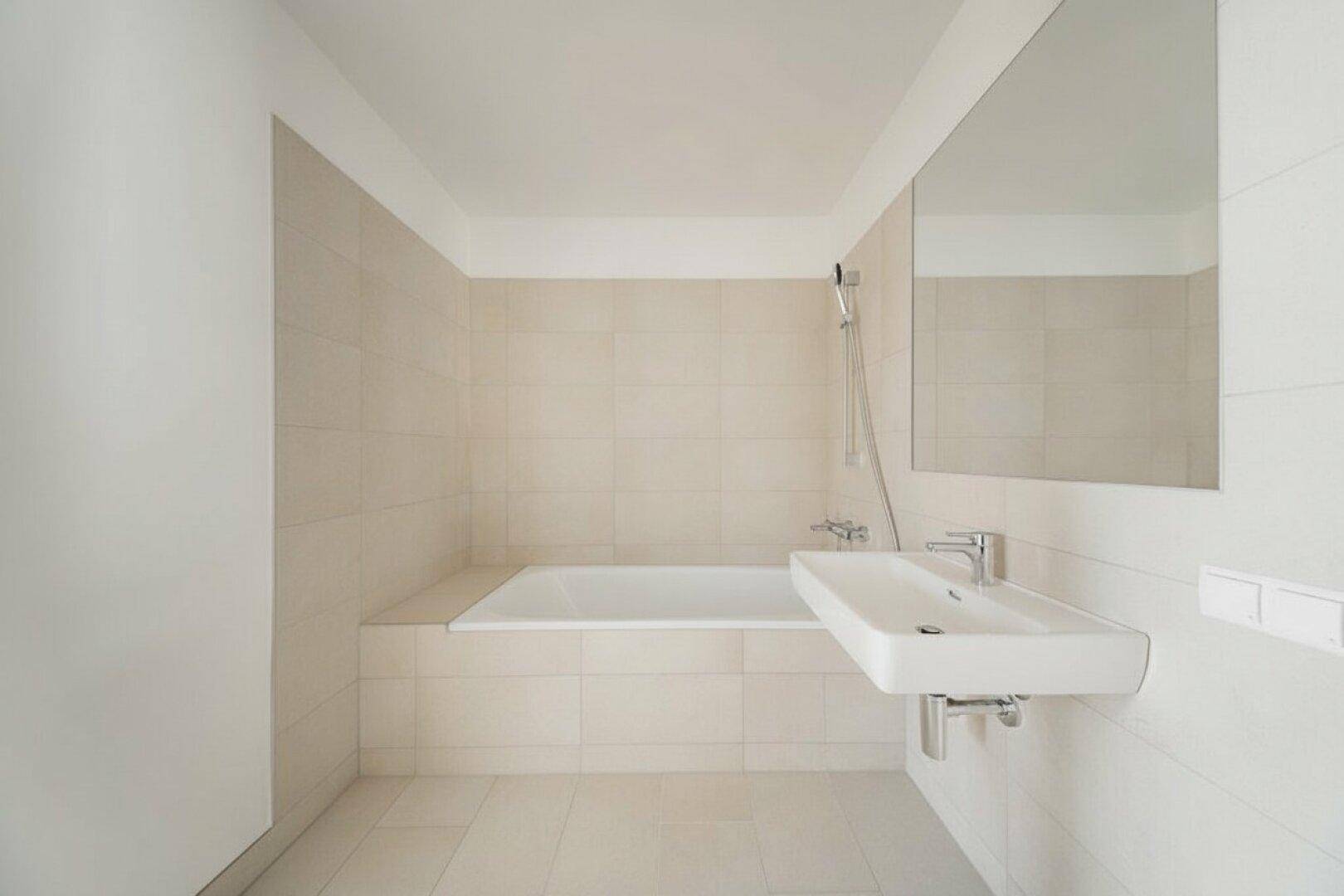 Modernes Badezimmer mit Badewanne, Waschbecken und großem Wandspiegel.