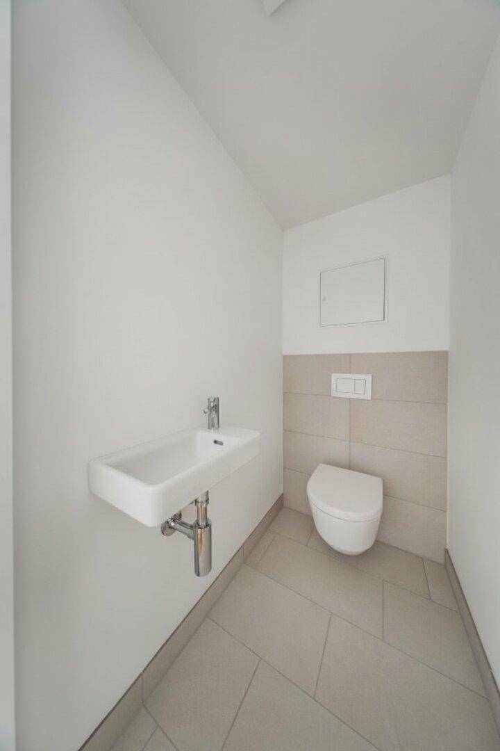 Modernes Gäste-WC mit wandhängendem WC und kleinem Waschbecken.