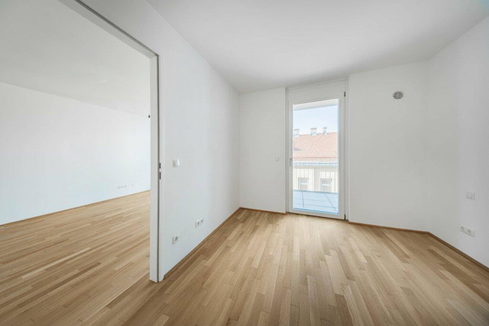 Zwei leere, helle Räume mit Parkettboden und Verbindungstür, ideal für flexible Nutzung.