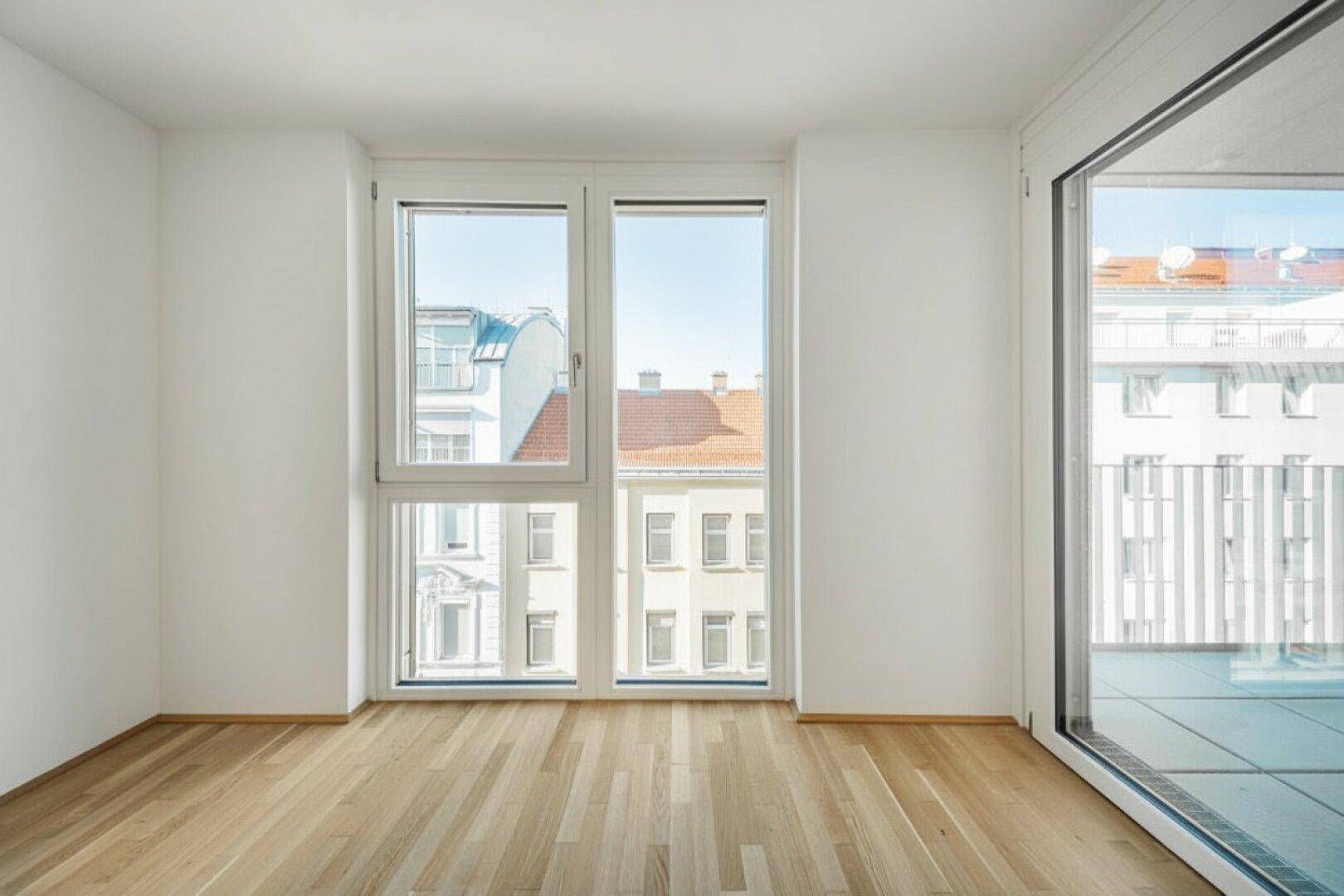 Heller Raum mit großen Fenstern und Parkettboden, bietet einen Blick auf die Stadt.