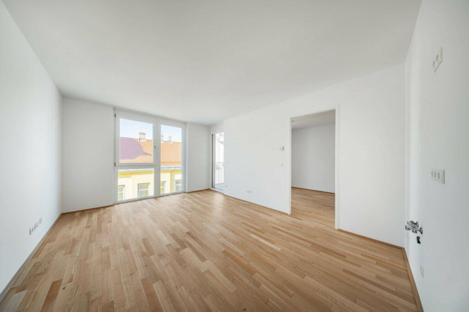 Geräumiger, heller Wohnbereich mit Parkettboden und großen Fenstern für viel Licht.