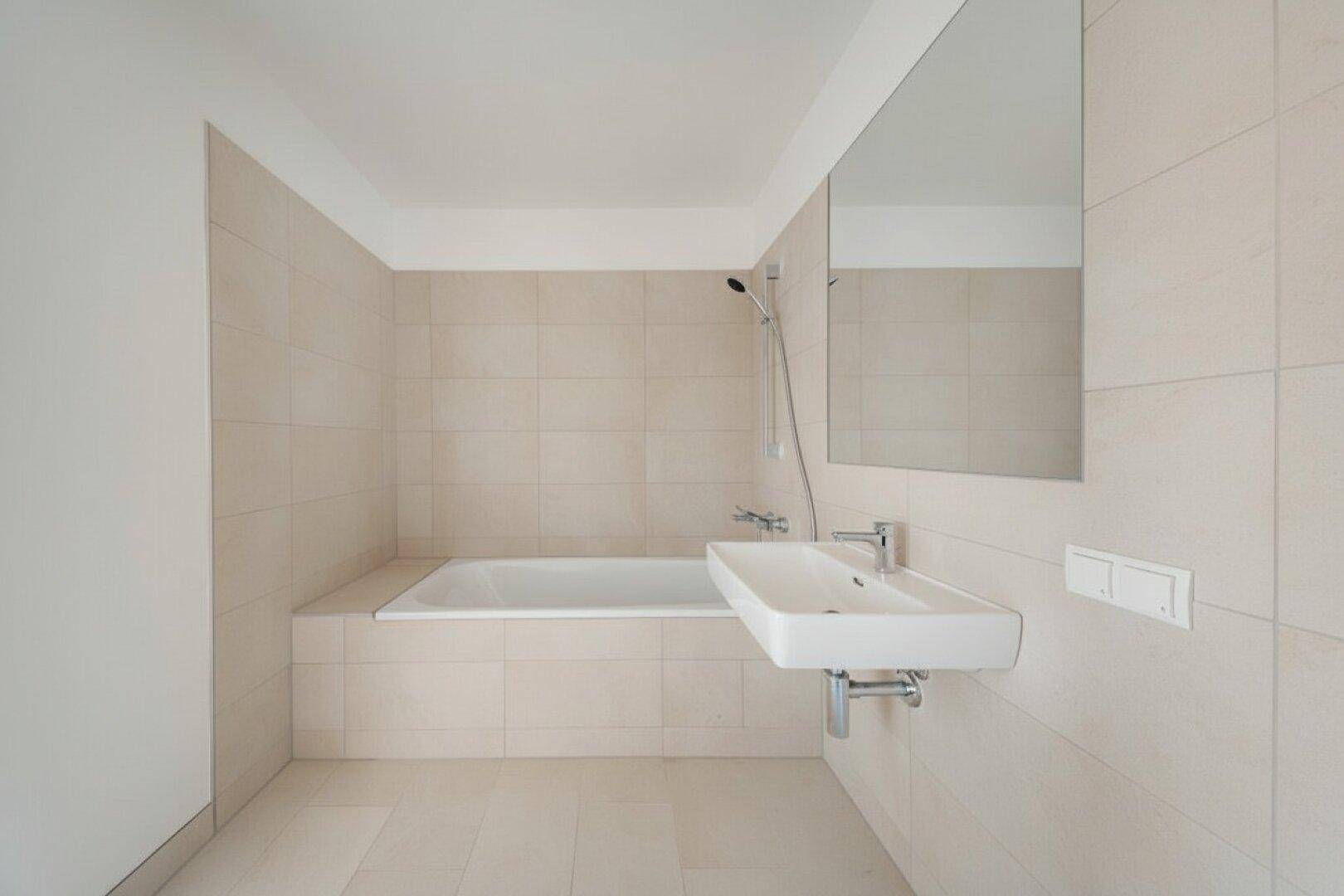 Helles Badezimmer mit Badewanne, modernem Waschbecken und großem Spiegel.