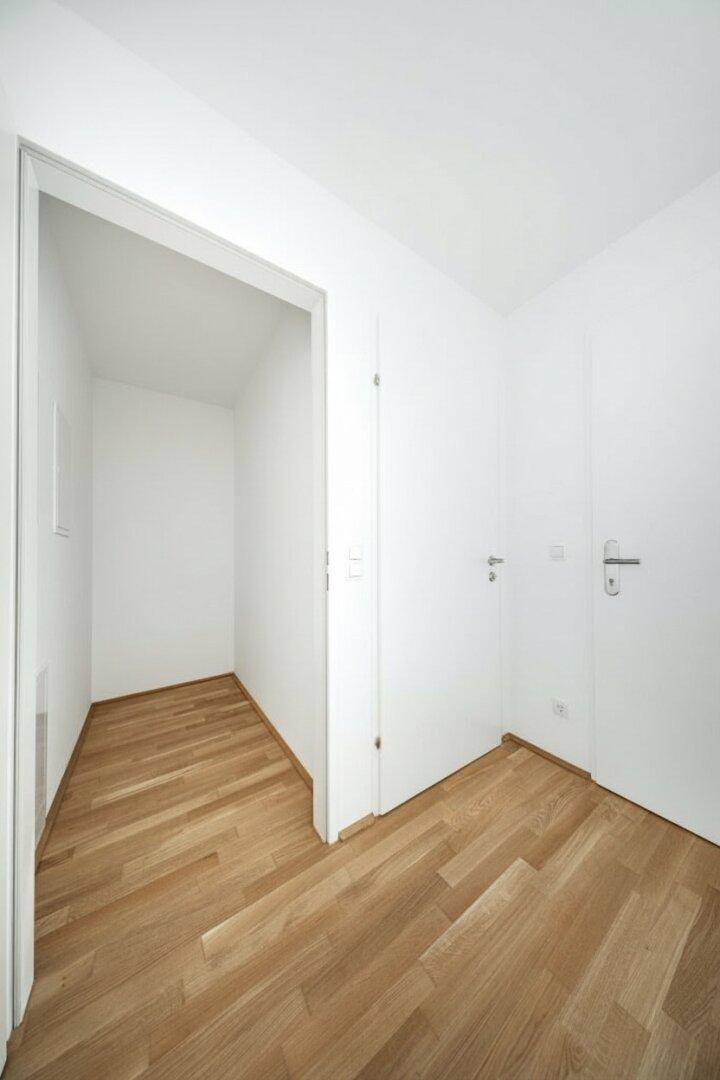 Kleiner, heller Raum mit Parkettboden und integrierter Nische, ideal als Abstellraum.