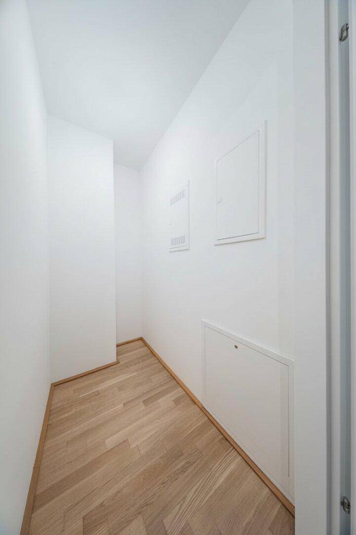 Kleiner, heller Abstellraum mit Parkettboden und weißen Wänden.