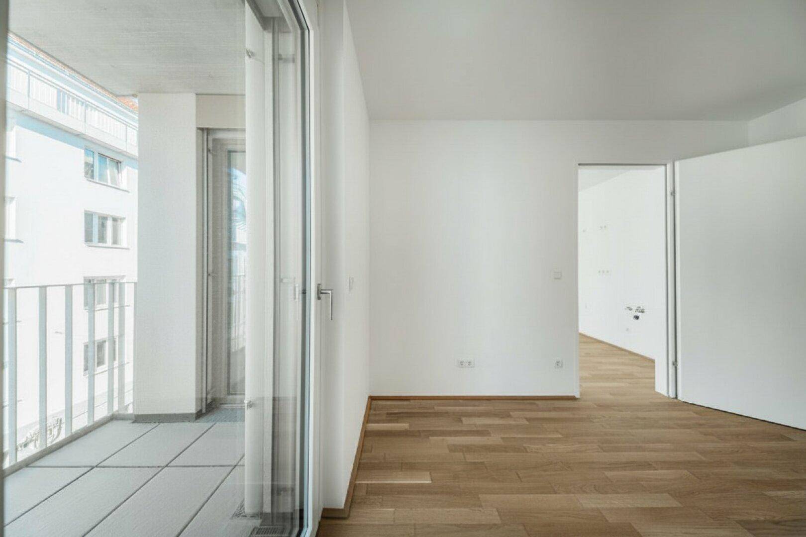 Heller Raum mit Parkettboden und direktem Zugang zu einem Balkon.