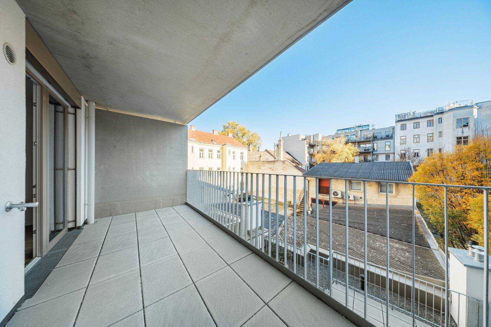 Geräumiger Balkon mit Fliesenboden und Blick über die Dächer der Stadt.