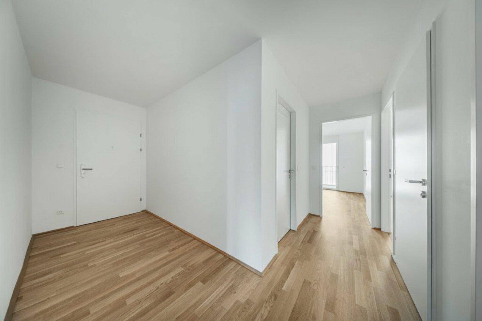 Heller Flur mit Holzboden und mehreren Türen, der verschiedene Räume verbindet.