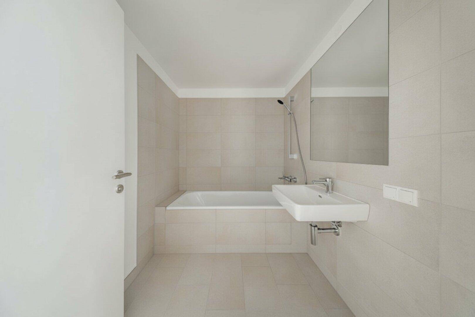 Modernes Badezimmer mit Badewanne, Dusche und Waschbecken, in hellen Beigetönen gefliest.