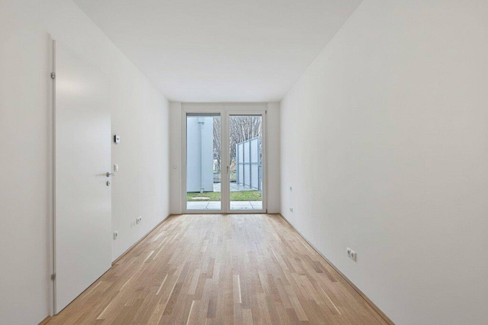 Heller Raum mit Holzboden und direktem Zugang zu einem Außenbereich.