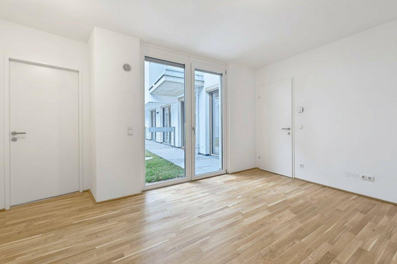 Heller Raum mit Holzboden und großen Fenstern, die viel Tageslicht hereinlassen.