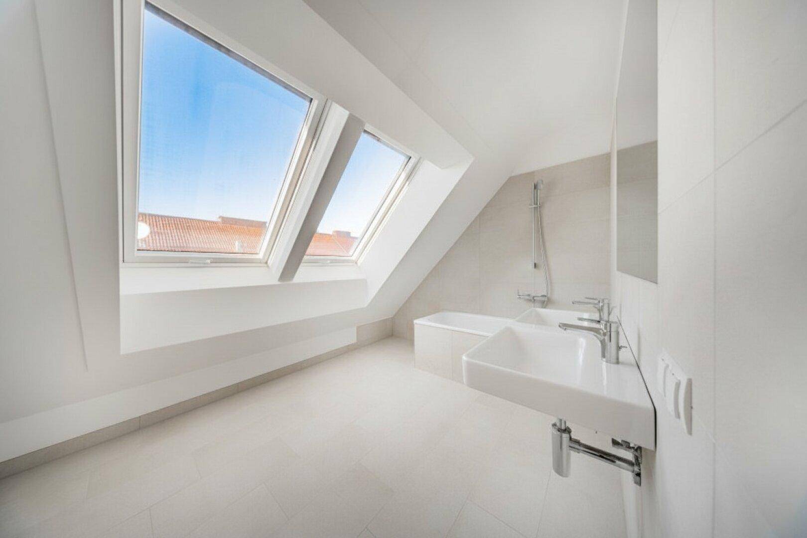 Geräumiges Badezimmer mit Fliesenboden, Badewanne, Doppelwaschbecken und hellen Dachfenstern.