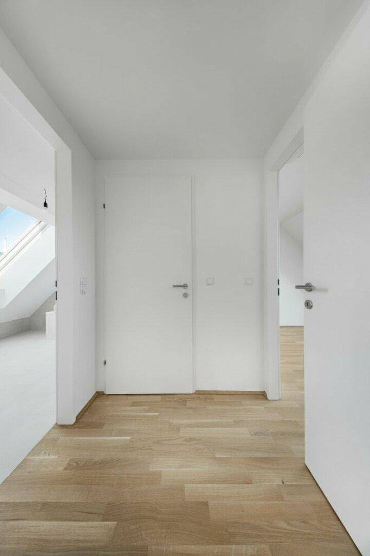 Heller Flur mit Holzboden und weißen Türen, der zu verschiedenen Räumen führt.