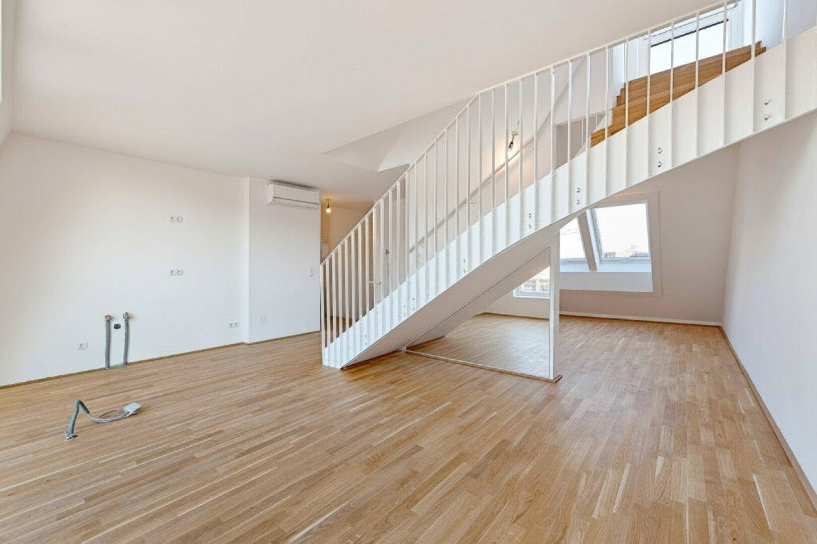 Heller Wohnbereich mit Holztreppe, Parkettboden und vorbereiteten Anschlüssen für individuelle Gestaltung.