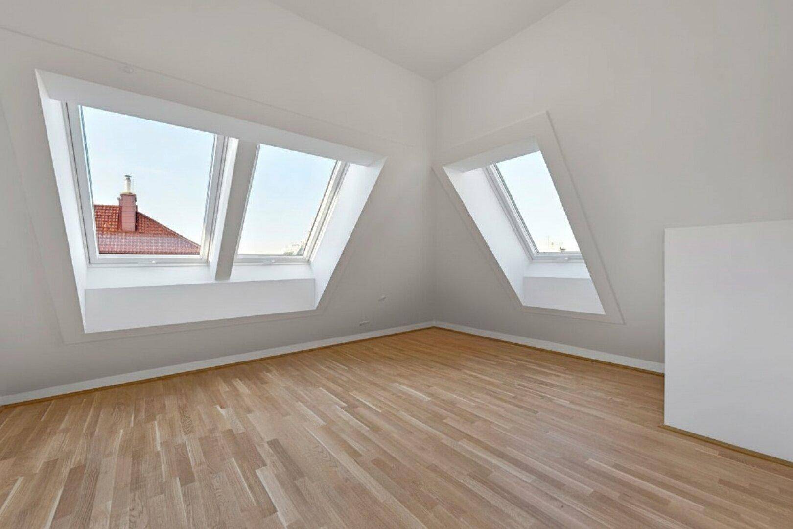 Geräumiger Dachgeschossraum mit zwei großen Dachfenstern, Holzboden und weitem Ausblick.