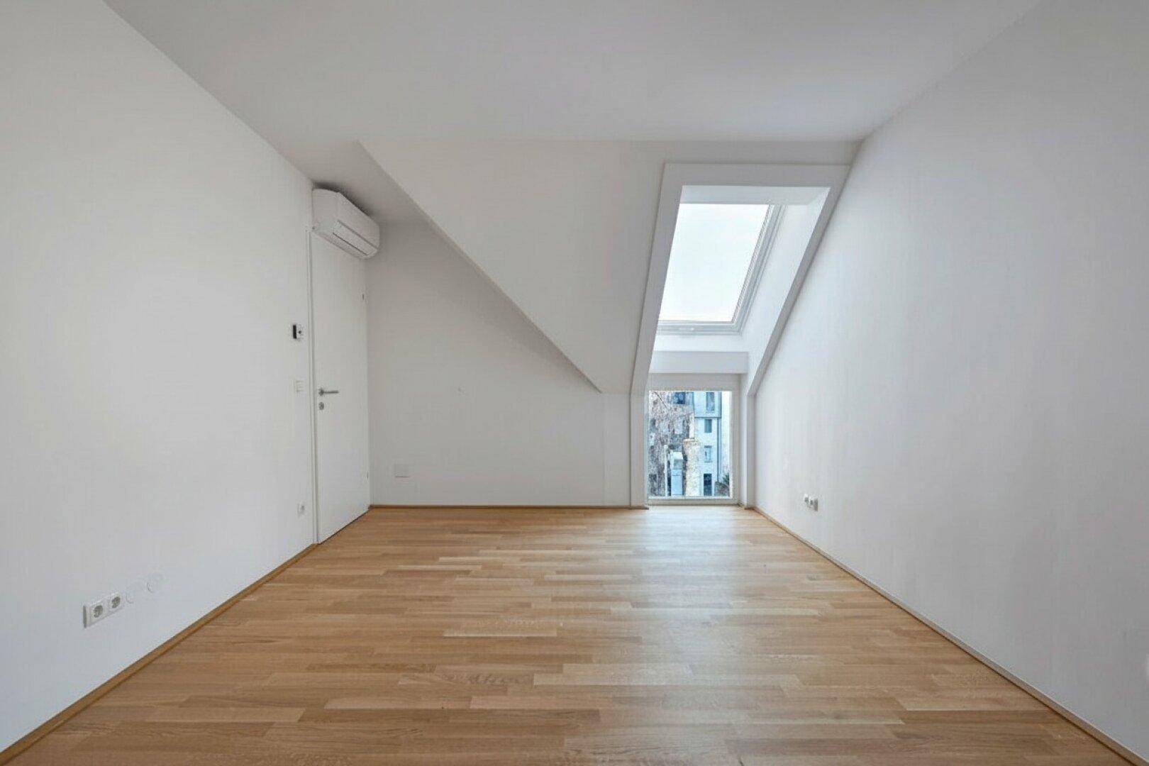 Schlafzimmer im Dachgeschoss mit Holzboden, Dachschräge und Oberlicht für viel Tageslicht.