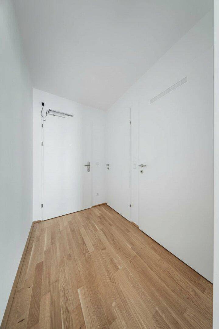 Schmaler Flur mit Holzboden und weißen Türen, der zu den Wohnbereichen führt.