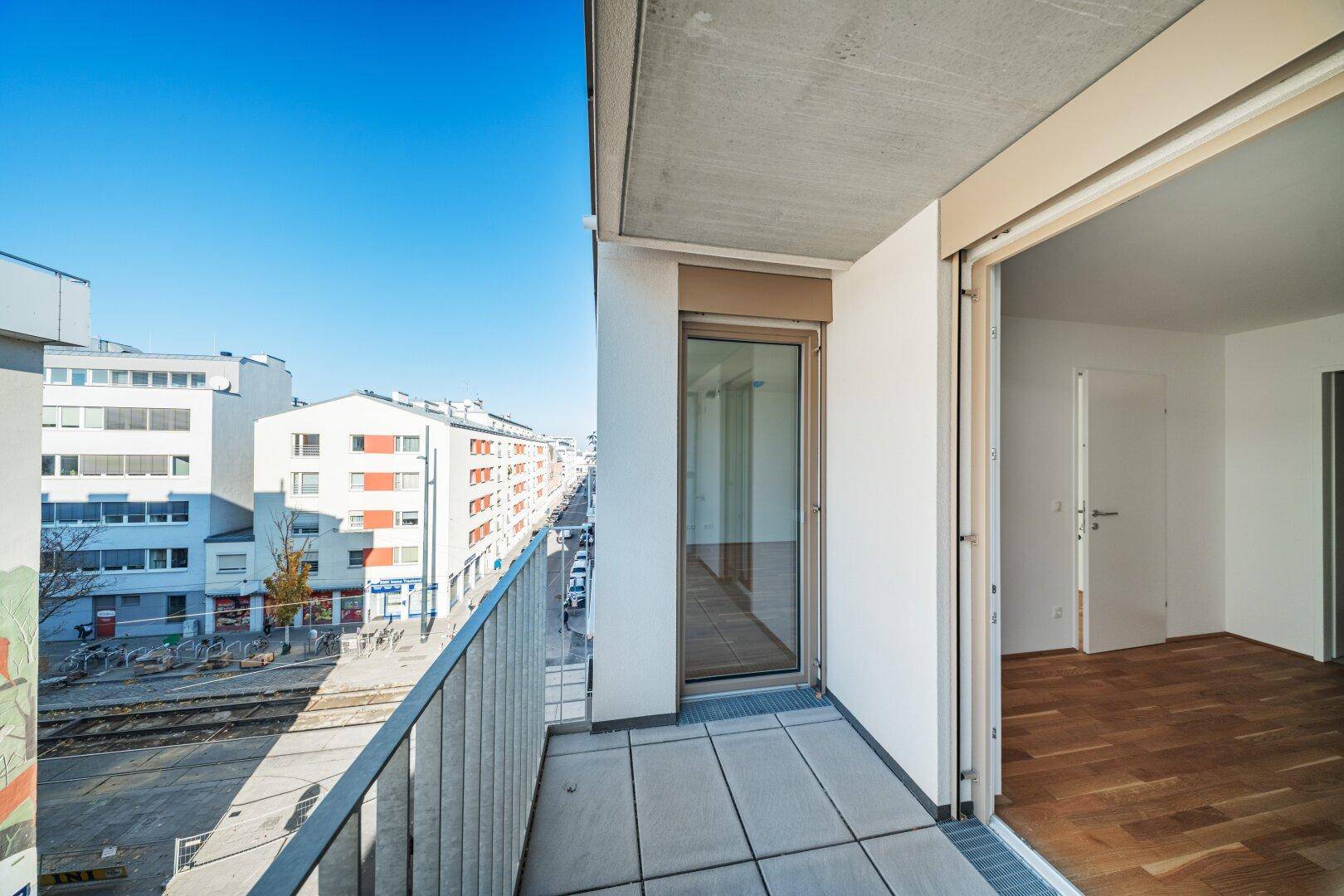 Geräumiger Balkon mit Weitblick über die Stadt und angrenzende Gebäude.
